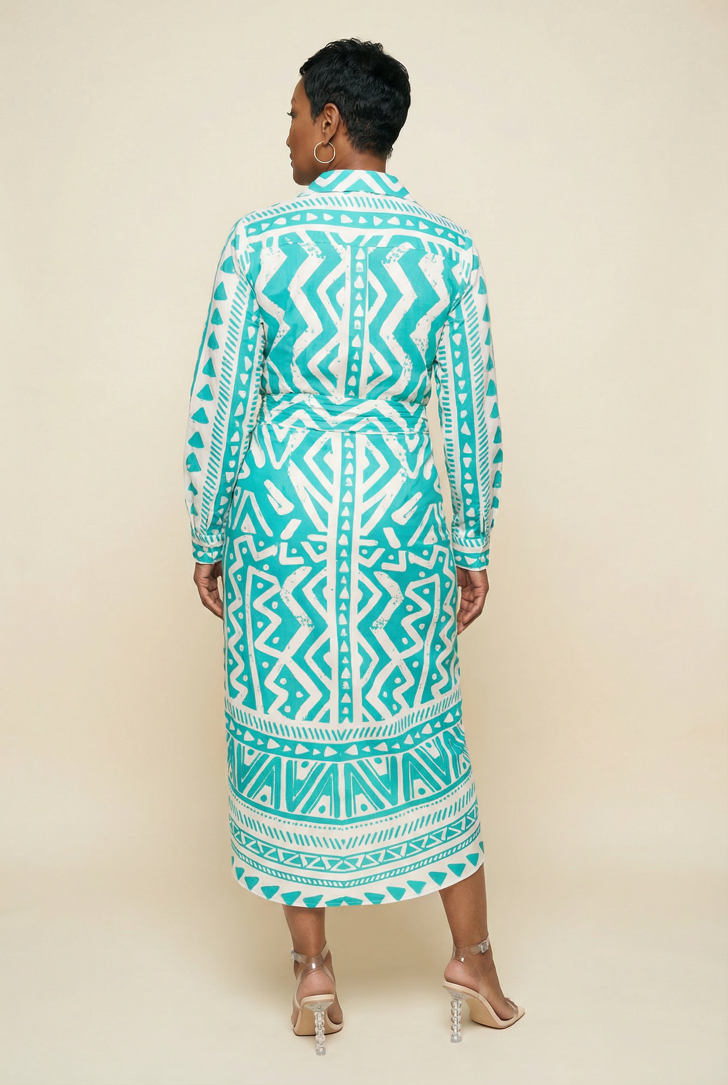 Woman wearing a teal and white patterned dress against a beige background