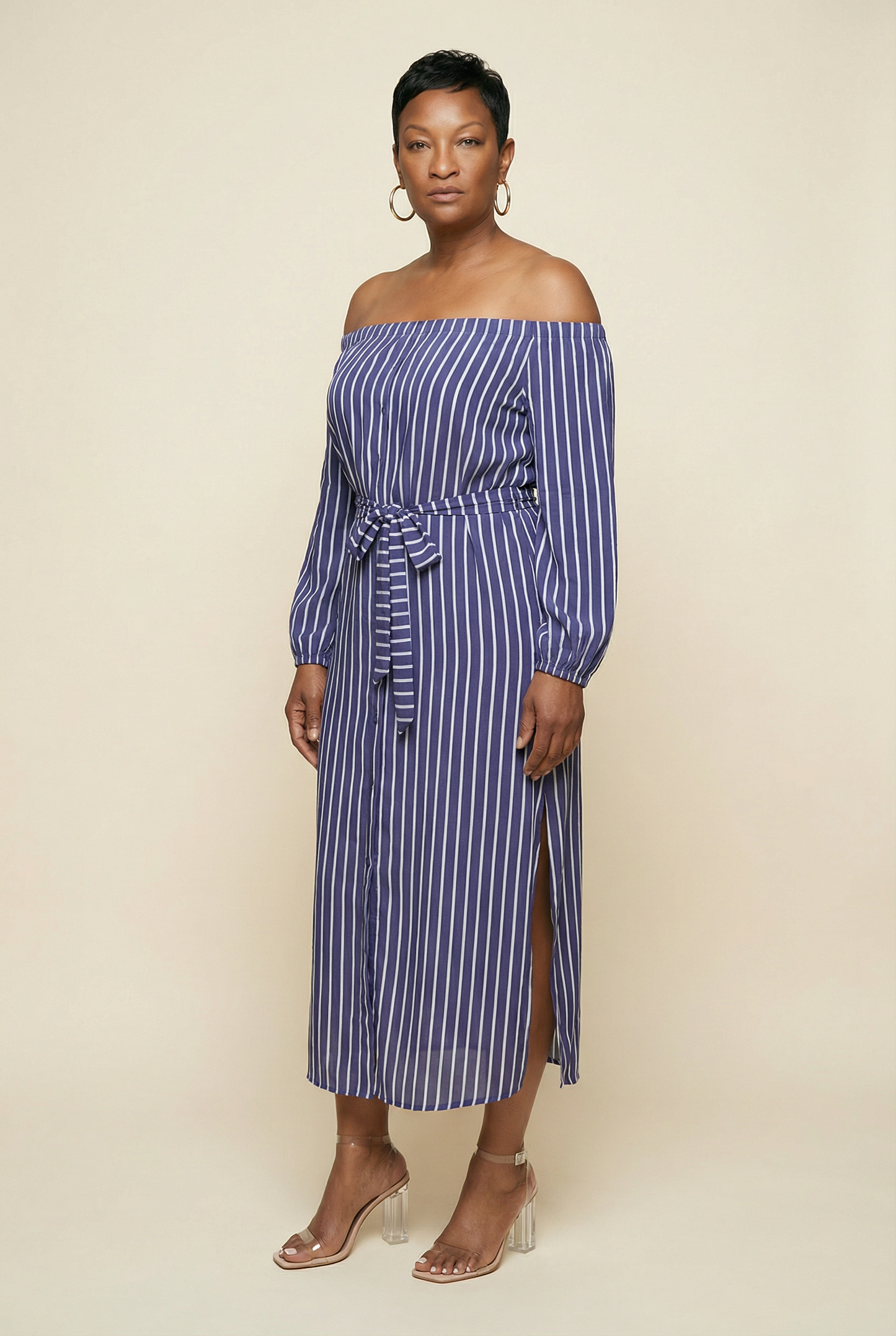 Woman wearing a blue and white striped off-shoulder dress on a beige background