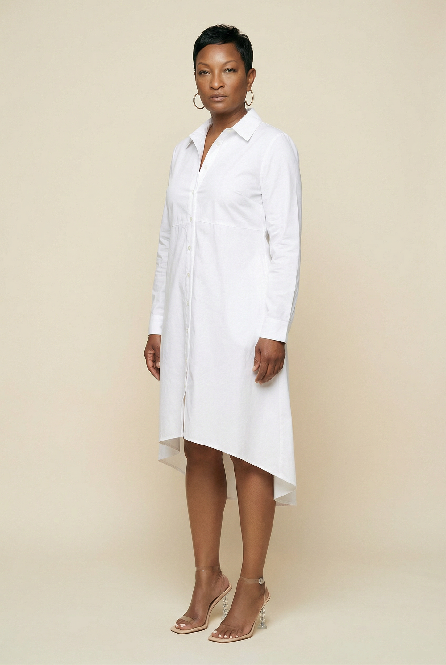 Woman wearing a white shirt dress against a beige background