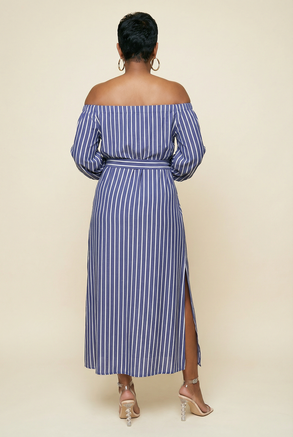 Woman wearing a blue and white striped off-shoulder dress with a slit on a beige background