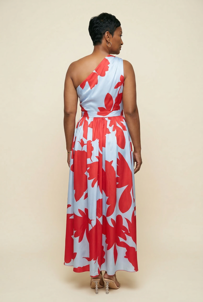 Woman wearing a red and white floral one-shoulder dress against a beige background